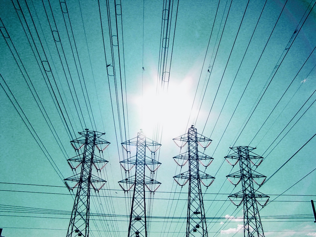 image of electricity pylons with blue background and sun